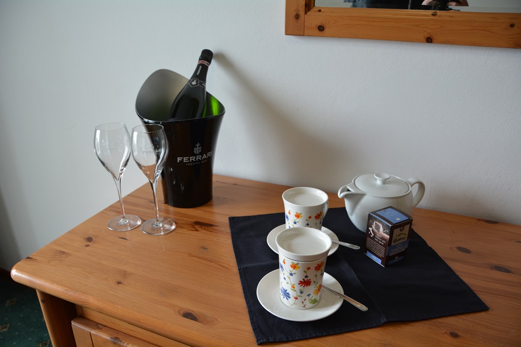 Dettagli accoglienti nelle camere dell’Hotel Polsa in Trentino con vino e tisane